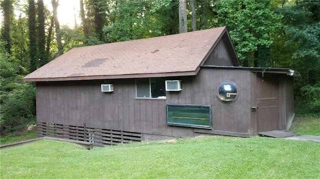 view of outdoor structure featuring a wall mounted air conditioner and a lawn