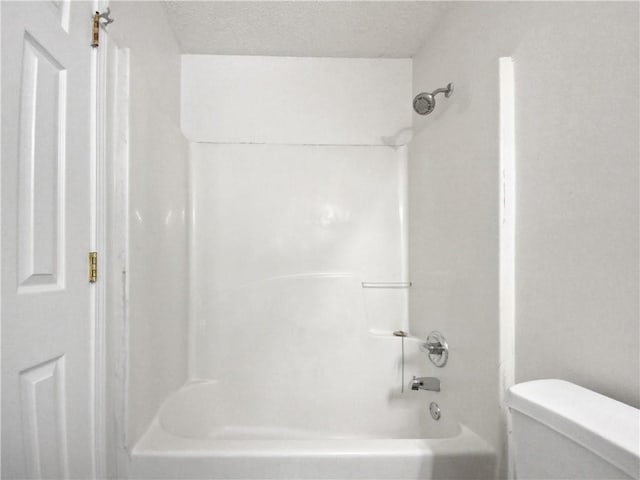 bathroom with tub / shower combination, a textured ceiling, and toilet