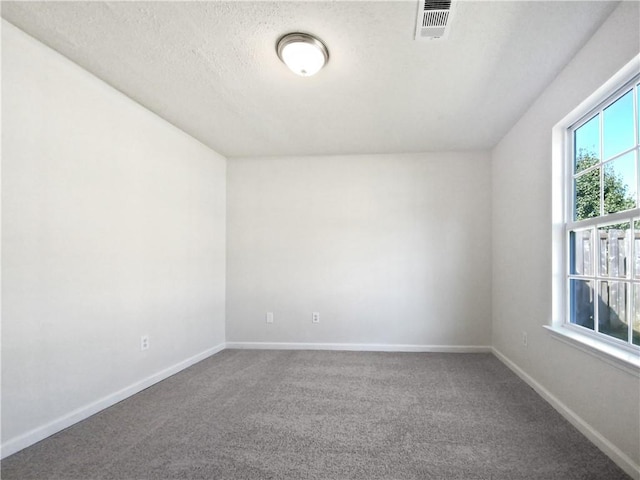 carpeted empty room featuring a textured ceiling