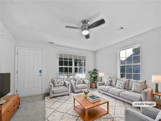 living room with a textured ceiling and ceiling fan