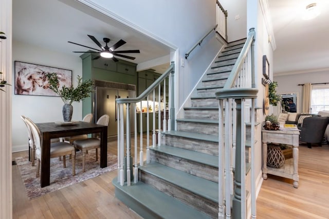 stairs featuring hardwood / wood-style flooring, ceiling fan, and crown molding