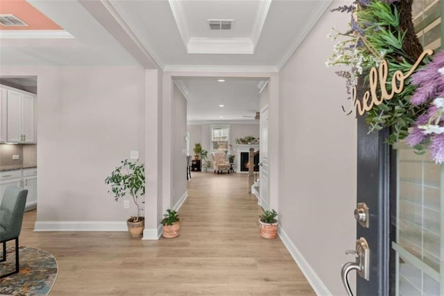 entryway featuring light hardwood / wood-style flooring, crown molding, and a tray ceiling