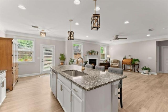 kitchen featuring dark stone counters, a wealth of natural light, sink, and white cabinets