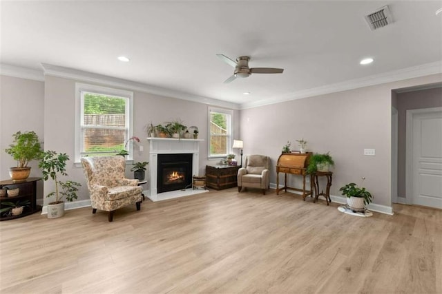 living area featuring ceiling fan, a healthy amount of sunlight, light hardwood / wood-style flooring, and ornamental molding