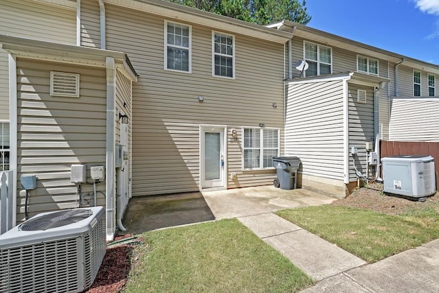 rear view of property with cooling unit and a yard