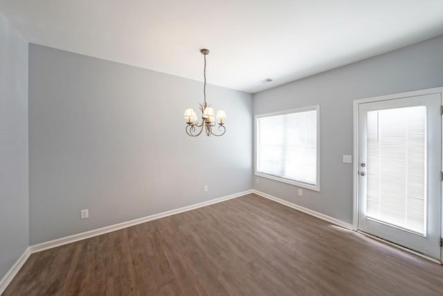 empty room featuring a notable chandelier and dark hardwood / wood-style flooring