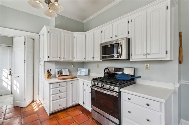 kitchen featuring crown molding, dark tile patterned floors, white cabinets, and appliances with stainless steel finishes