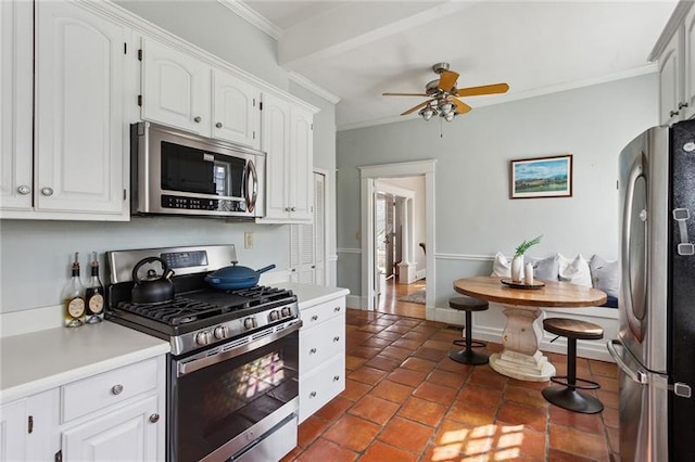 kitchen with ceiling fan, ornamental molding, white cabinets, and appliances with stainless steel finishes