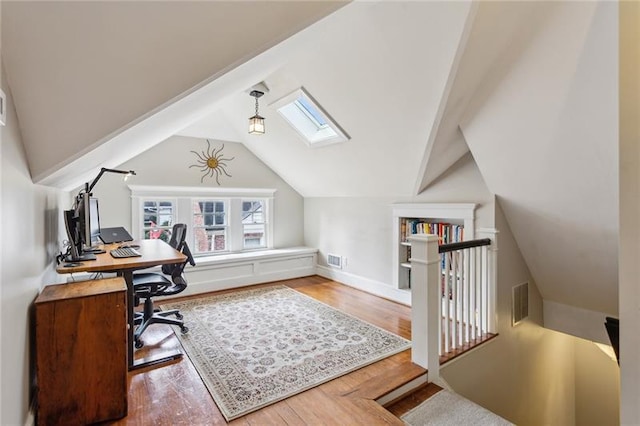 home office with hardwood / wood-style floors and vaulted ceiling with skylight