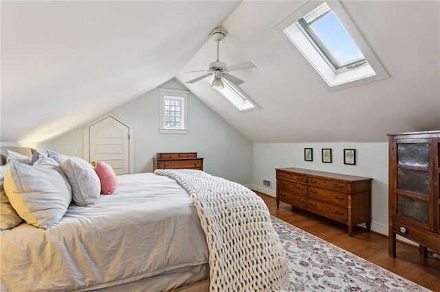 bedroom with dark hardwood / wood-style flooring, lofted ceiling with skylight, and ceiling fan