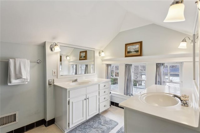 bathroom with a healthy amount of sunlight, lofted ceiling, and vanity