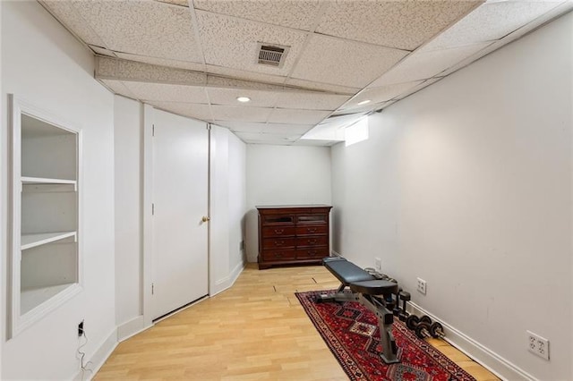 exercise area featuring a paneled ceiling and light hardwood / wood-style floors