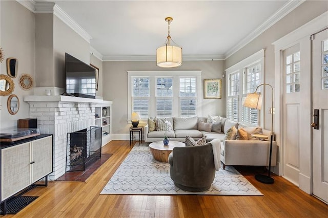 living room with hardwood / wood-style flooring, ornamental molding, a brick fireplace, and a wealth of natural light