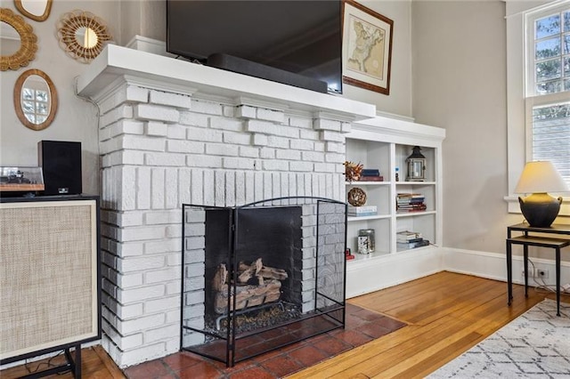 living room featuring a brick fireplace and dark wood-type flooring