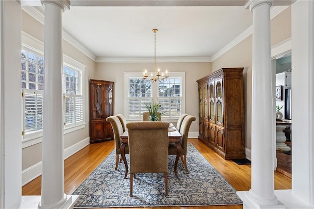 dining room with a healthy amount of sunlight, a chandelier, light hardwood / wood-style flooring, and ornate columns