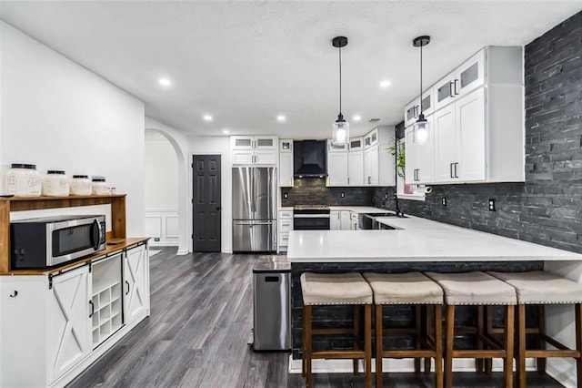 870 Underhill Ct, Sugar Hill, GA 30518 - kitchen featuring stainless steel appliances, exhaust hood, a peninsula, backsplash, and arched walkways