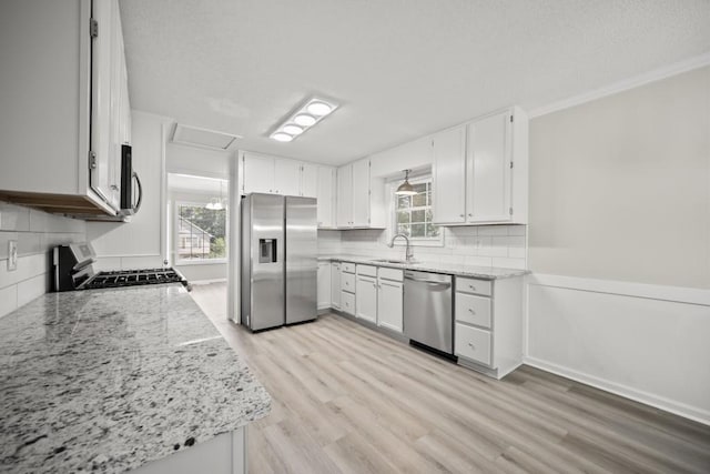 990 Trestle Dr, Austell, GA 30106 - kitchen featuring appliances with stainless steel finishes, tasteful backsplash, light wood-type flooring, light stone counters, and ornamental molding