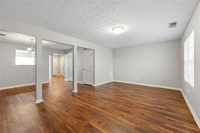 spare room featuring dark wood-style floors, visible vents, a textured ceiling, and baseboards