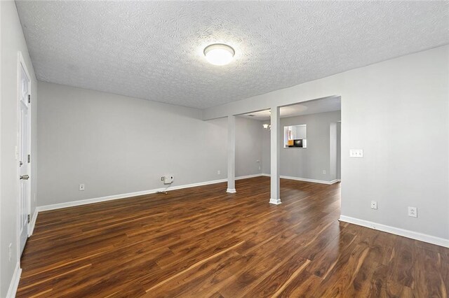 interior space with dark wood-style floors, a textured ceiling, and baseboards