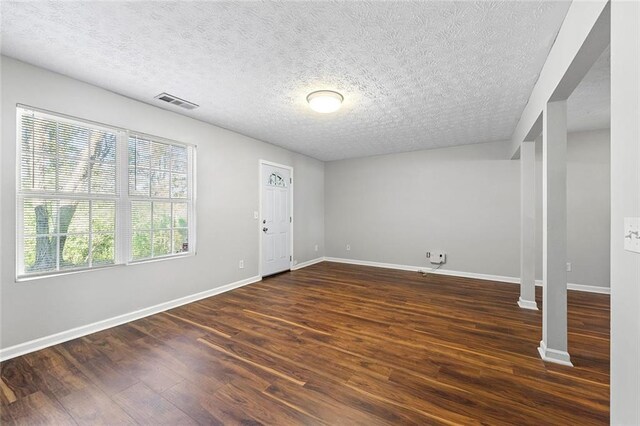 foyer with dark wood-style flooring, visible vents, a textured ceiling, and baseboards