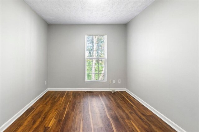 spare room with baseboards, dark wood finished floors, and a textured ceiling