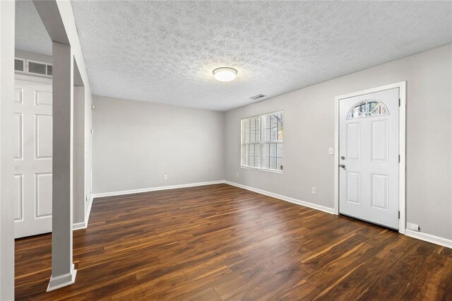 entrance foyer featuring dark wood-style floors, baseboards, visible vents, and a textured ceiling