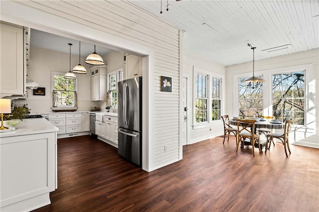 kitchen featuring appliances with stainless steel finishes, dark hardwood / wood-style floors, pendant lighting, range hood, and white cabinets