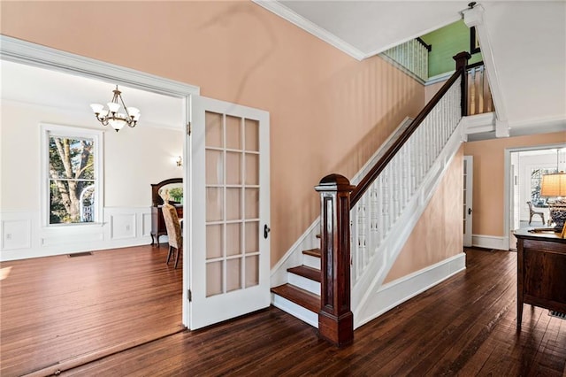 staircase with hardwood / wood-style flooring, ornamental molding, and a chandelier