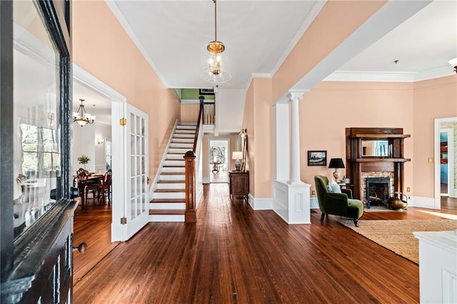 entrance foyer with decorative columns, crown molding, and dark wood-type flooring