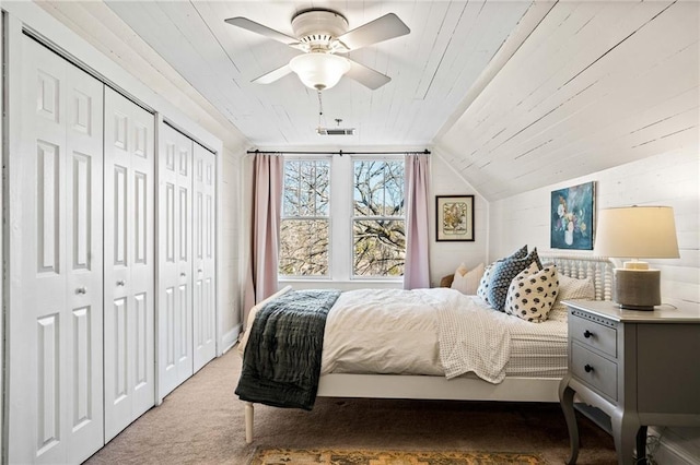 bedroom featuring carpet, two closets, lofted ceiling, and wood ceiling