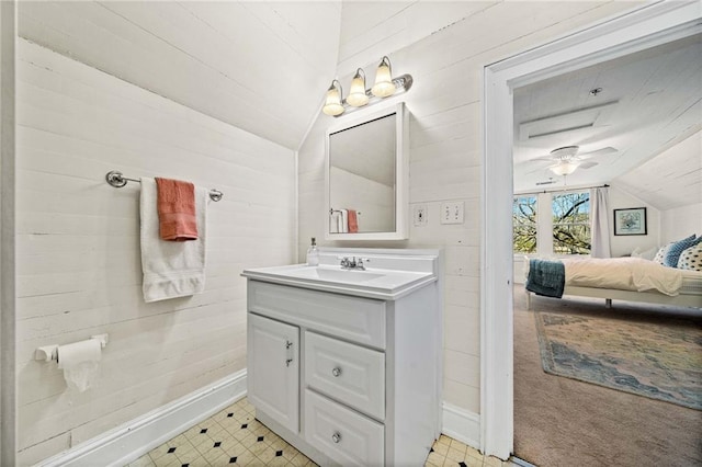 bathroom with vanity, vaulted ceiling, wooden walls, and ceiling fan