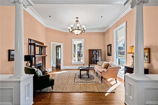 sitting room featuring hardwood / wood-style floors, crown molding, and ornate columns