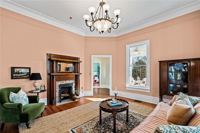 living room with hardwood / wood-style flooring, ornamental molding, a chandelier, and a fireplace