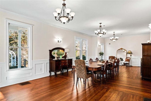 dining area with dark wood-type flooring, crown molding, and a chandelier