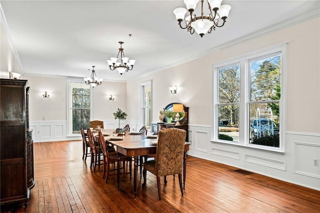 dining space with an inviting chandelier, ornamental molding, and hardwood / wood-style flooring