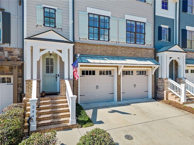 doorway to property with driveway, a garage, metal roof, a standing seam roof, and brick siding