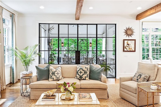 living area featuring plenty of natural light, baseboards, and beam ceiling