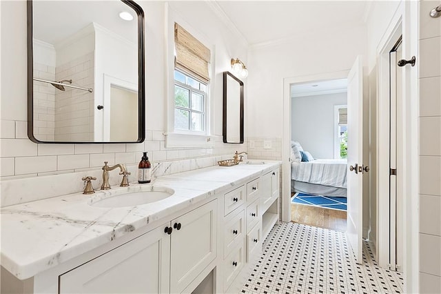 ensuite bathroom featuring double vanity, tile patterned floors, ornamental molding, and a sink