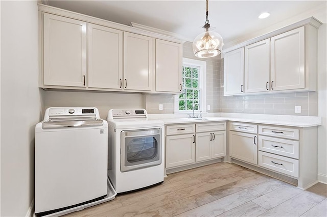 washroom with light wood finished floors, a chandelier, a sink, cabinet space, and independent washer and dryer