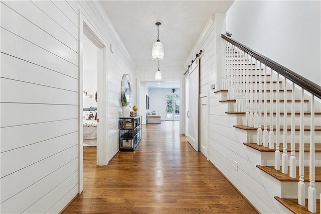 hallway featuring stairway, a barn door, and wood finished floors