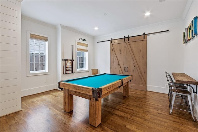 recreation room with baseboards, a barn door, ornamental molding, and wood finished floors