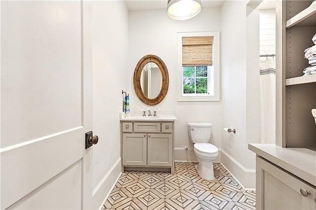 bathroom featuring baseboards, vanity, and toilet