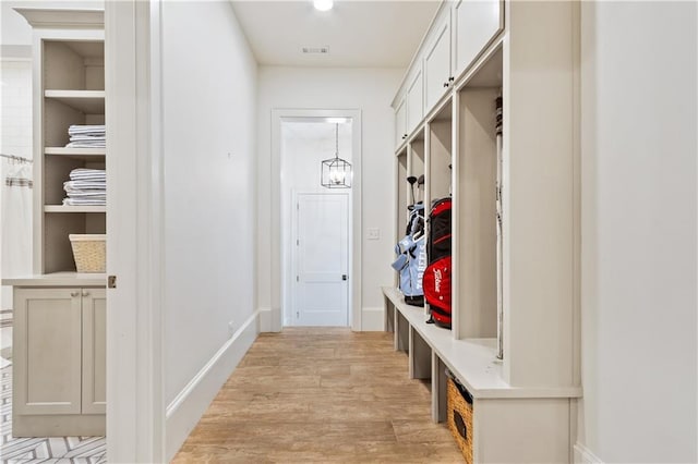 mudroom with a notable chandelier, baseboards, visible vents, and light wood-style flooring