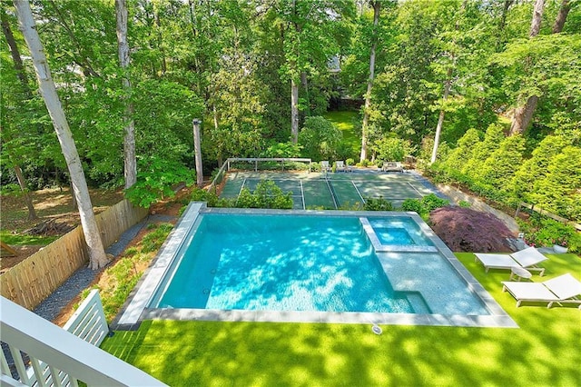 view of swimming pool featuring a lawn, a pool with connected hot tub, and fence