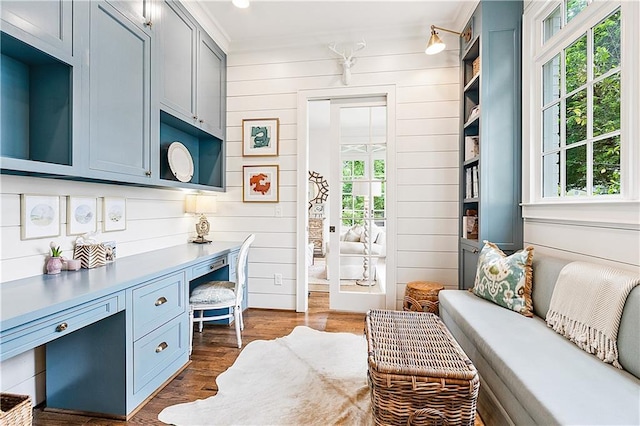 interior space featuring built in study area, crown molding, wood walls, and dark wood-type flooring