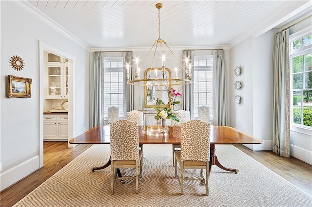 dining area featuring light wood-style floors, baseboards, crown molding, and a chandelier