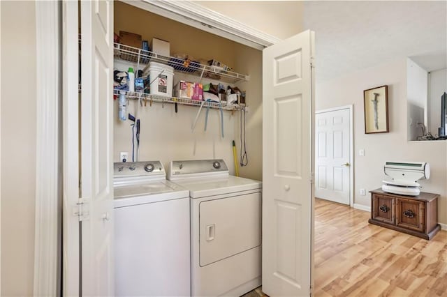 clothes washing area with washer and clothes dryer and light hardwood / wood-style floors