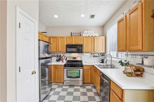 kitchen with appliances with stainless steel finishes, sink, and a textured ceiling