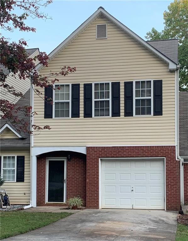 view of front of house with an attached garage, brick siding, and driveway