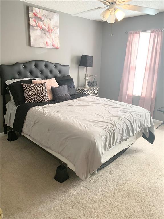 bedroom with a textured ceiling, a ceiling fan, and carpet floors
